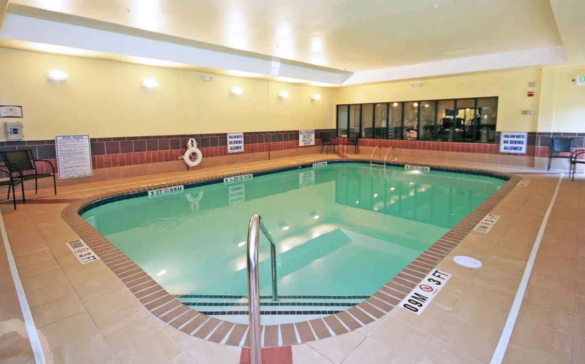 This image shows a welcoming indoor swimming pool area with comfortable seating and a pool ladder. The space is bright and inviting, ideal for relaxation and informal group gatherings. The seating area suggests a spot for socializing or winding down after a day of exploration.