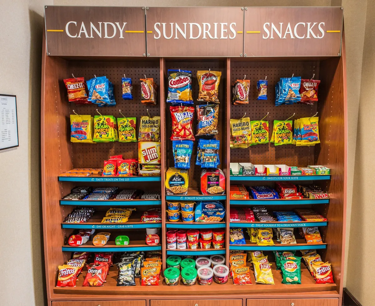 A cheerful grab-and-go area displaying a variety of snacks, candies, and sundries. The colorful display is inviting and suggests convenient options for quick bites or supplementing home-cooked meals.