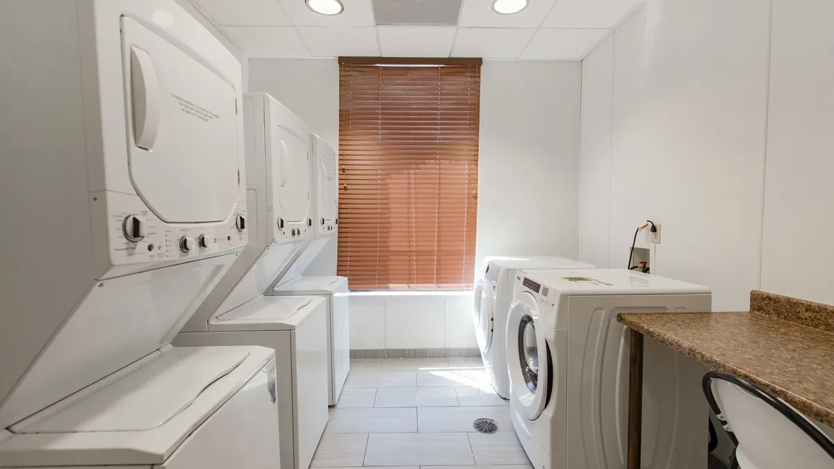 A well-organized laundry room with several washing machines and dryers, a spacious countertop for folding clothes, and a clean, practical layout—emphasizing convenience for guests.