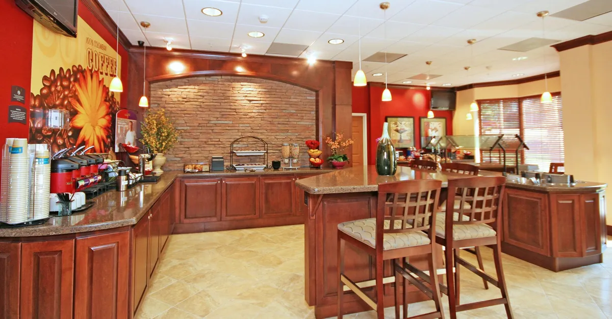 A cozy interior view highlighting a dedicated coffee station set against a decorative stone wall. In the foreground, a seating area invites guests to relax, while the setup suggests easy access to light dining and refreshments.