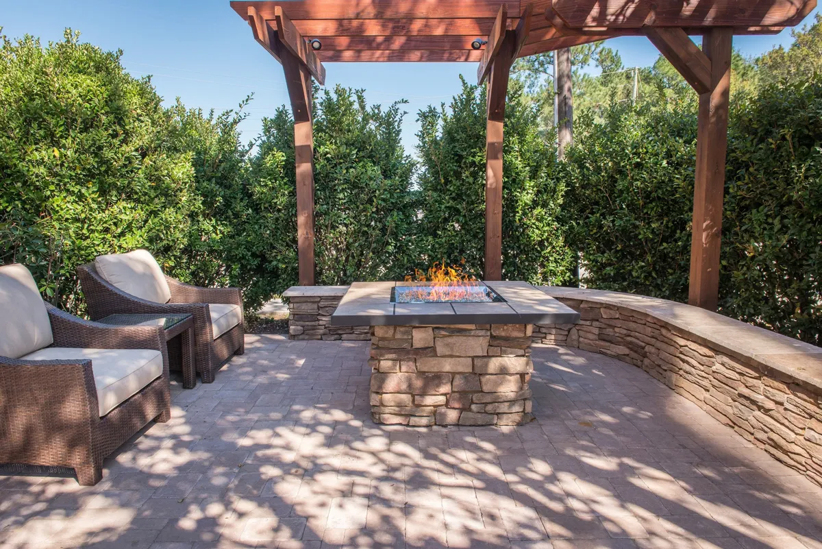 This cozy outdoor space features a fire pit surrounded by comfortable seating under a pergola, all set against lush greenery. The ambiance is warm and communal, perfect for evening gatherings, story sharing, or unwinding after a day of exploration. The sunset glow adds to the inviting feel of the area.